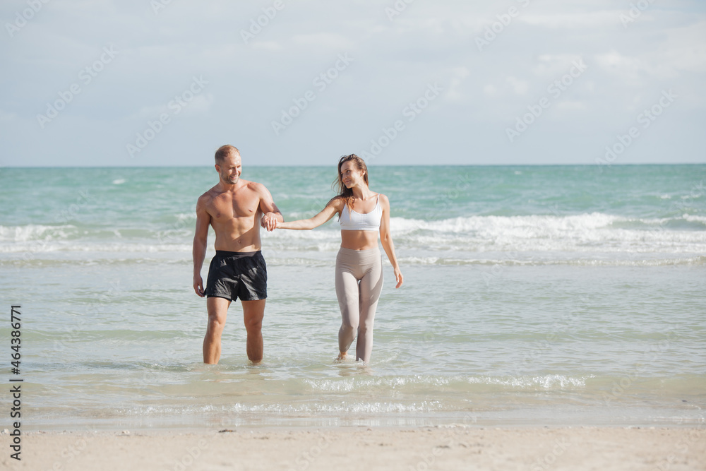 young couple walking at each other at beach. Romantic couple walking on sea, enjoying life and each other at honeymoon vacation.
