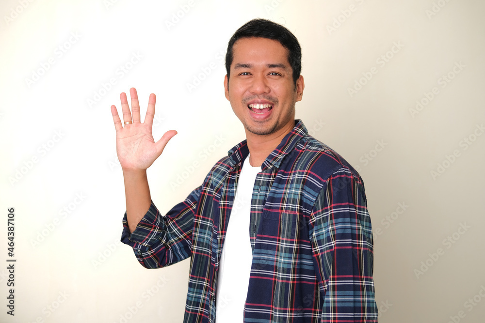 Side view of adult Asian man smiling happy while waving his hand Side view of adult Asian man smiling happy while waving his hand