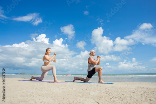 fitness, sport, and lifestyle concept - couple making yoga exercises on beach, Man and woman doing yoga exercise on the beach.
