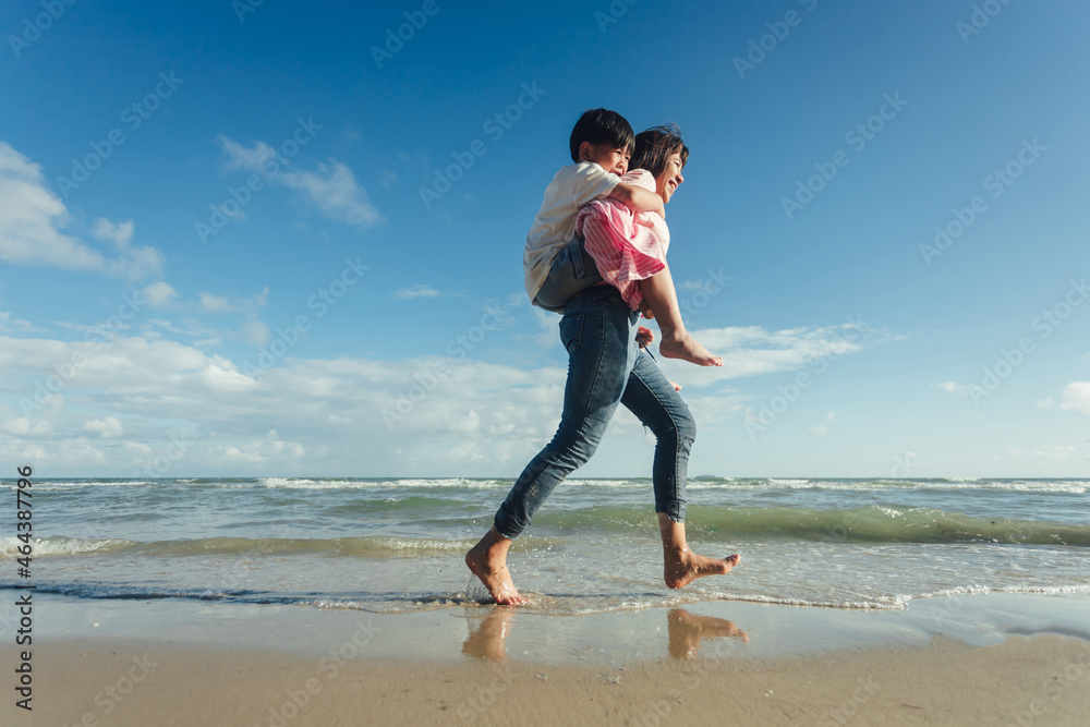 Young happy beautiful mother and her daughter having fun on the beach. Young family asian on vacation have a lot of fun