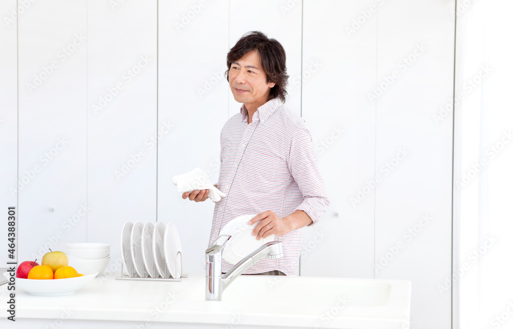 キッチンでお皿を拭く中高年男性 キッチンでお皿を拭く中高年男性