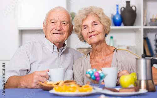 Happy senior couple enjoying conversation over cup of coffee at home