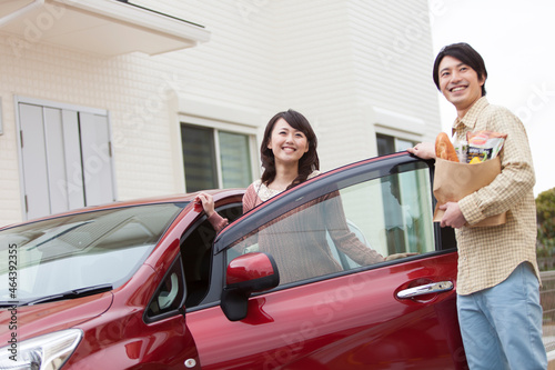 買い物袋を持つ男性と車から降りる女性 photo