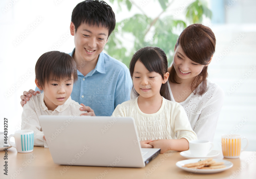 ノートパソコンを見ている4人家族