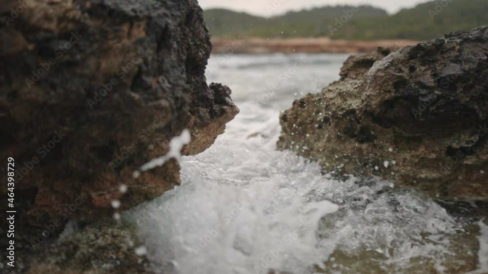 Wave crashes through rocks at the beach, slow motion, low gimbal zoom in Wave crashes through rocks at the beach, slow motion, low gimbal zoom in