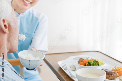 食事介助をする女性介護士とシニア男性 photo