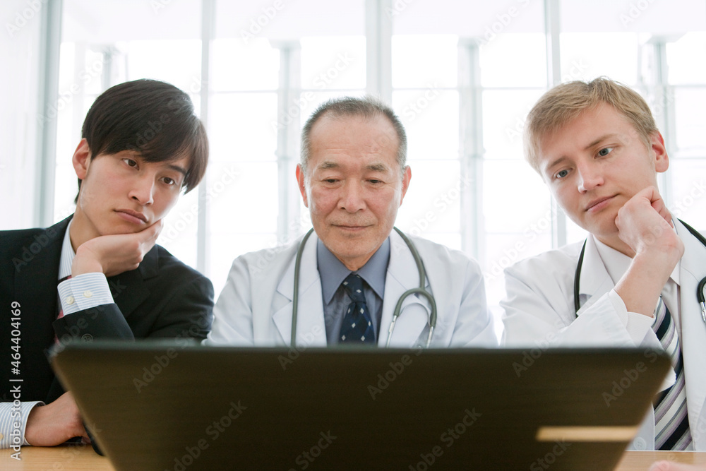 ノートパソコンを見るビジネスマンと医師3人