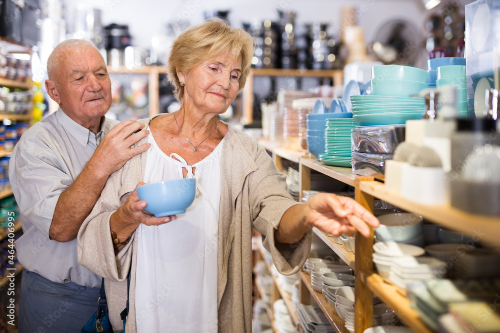 Portrait of an elderly couple in tableware store - making a selection of new plates and cups