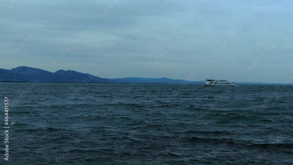 A far away ferry sailing across lake constance with the alps in the background A far away ferry sailing across lake constance with the alps in the background