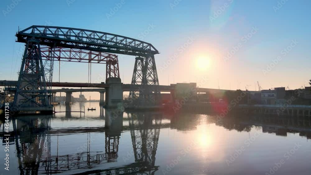Low level aerial push out shot of ferry bridge Nicolas Avellaneda over the Matanza River during sunrise with sun flare. Low level aerial push out shot of ferry bridge Nicolas Avellaneda over the Matanza River during sunrise with sun flare.