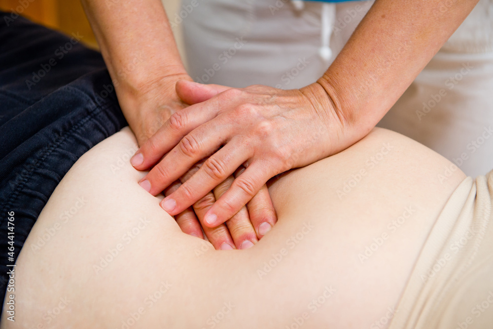 Hands of a specialist giving a massage to a client lying on a massage table.