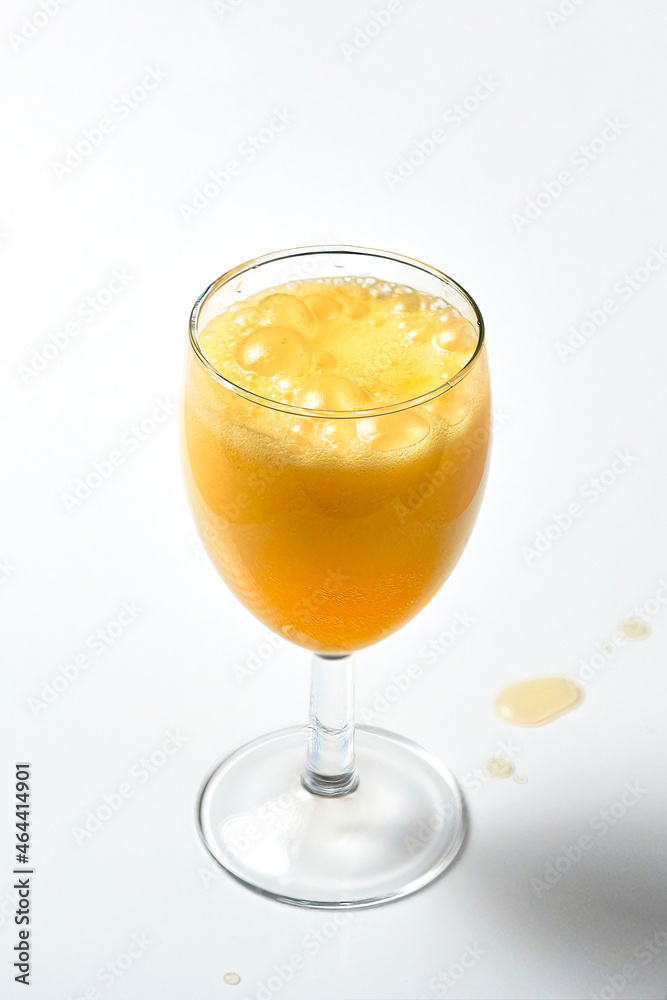 Glass goblet with bubbling orange liquid on a white background. Glass goblet with bubbling orange liquid on a white background.