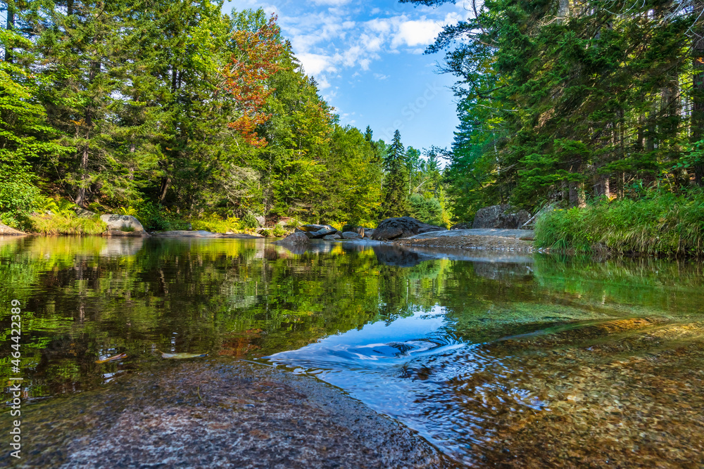 Smooth, mirror-like water reflects an autumn forest on a river in the foothills of Mount Washington in the White Mountain National Forest in New Hampshire. Smooth, mirror-like water reflects an autumn forest on a river in the foothills of Mount Washington in the White Mountain National Forest in New Hampshire.