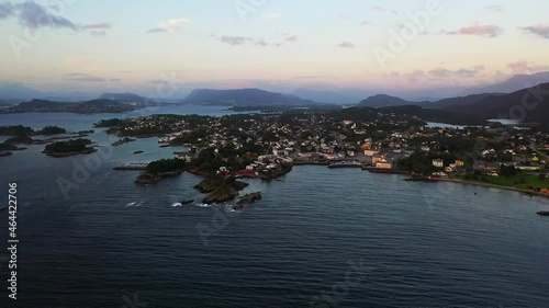 Aerial view overlooking a town harbor near Alesund, sunset in Norway - approaching, drone shot photo