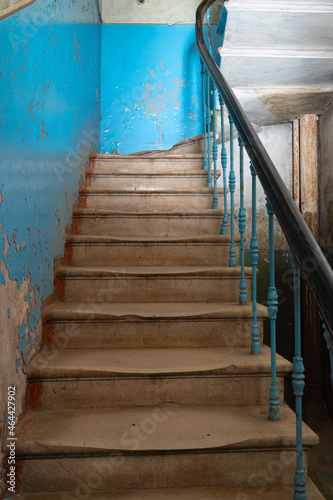 Old abandoned concrete staircase with beautiful railings in an empty building with blue walls