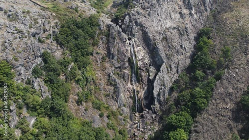 Lichen covered massive cliff wall with stream fresh waterfall, Cascata da Frecha da Mizarela, Arouca, Portugal photo