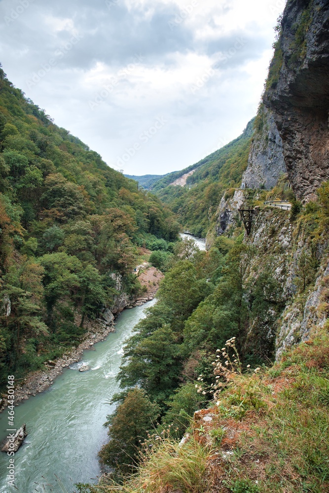 The mountain road goes into a gorge between a sheer cliff and a cliff. The river is deep at the bottom of the gorge.