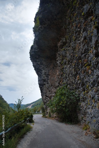 Wallpaper Mural The mountain road runs along the cliff at the cliff. Rocks hang over the road and the abyss. Torontodigital.ca