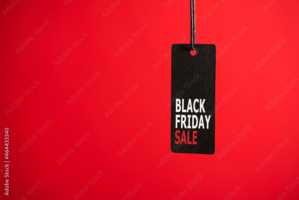 Photo of hanging black price tag on isolated red background with text