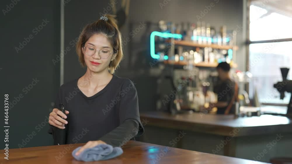 Asian woman barista using towel sweeping counter bar with alcohol sanitizer before opening cafe. Female coffee shop owner clean up table for service to customer. Small business owner working concept Asian woman barista using towel sweeping counter bar with alcohol sanitizer before opening cafe. Female coffee shop owner clean up table for service to customer. Small business owner working concept