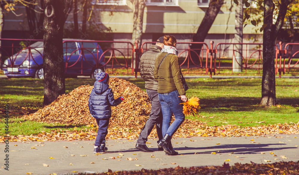 Obraz premium A married couple walks with their son in the autumn park