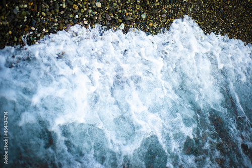 Marine backgrounds. The sea foam absorbs the pebble beach. Dark pebbles and a seething sea.