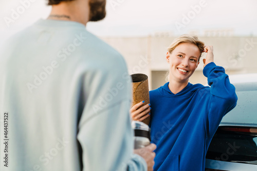 Young man and woman smiling and talking during workout on parking