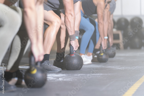 Group of faceless athletes working out with kettlebells in a cross training center