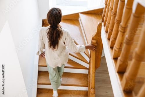 Fotografie Young black woman wearing pajama walking upstairs
