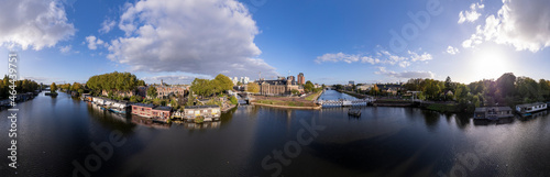 360 degree aerial panorama of canal in Utrecht with floating home boats and Muntgebouw against a blue sky with cumulus clouds above. Urban housing cityscape concept.