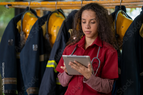 Portrait of confident fire woman in medical coat standing at fire station. © visoot