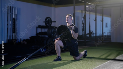 Fitness man exercise landmine press with barbell while kneel weightlifting photo