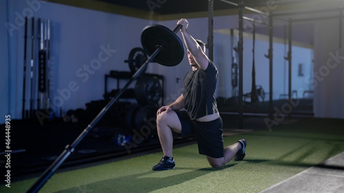 Fitness man exercise landmine press with barbell while kneel weightlifting photo