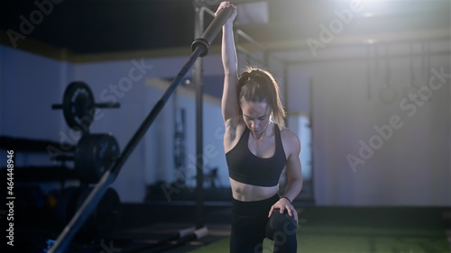 Fitness woman  exercise landmine press with barbell while kneel weightlifting photo