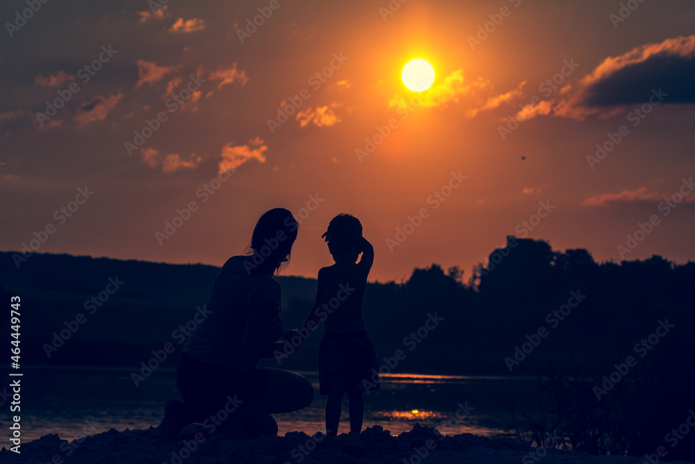 woman and child on sunset background over summer river.