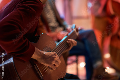 Close-up of man sitting on chair and learning to play guitar during lesson