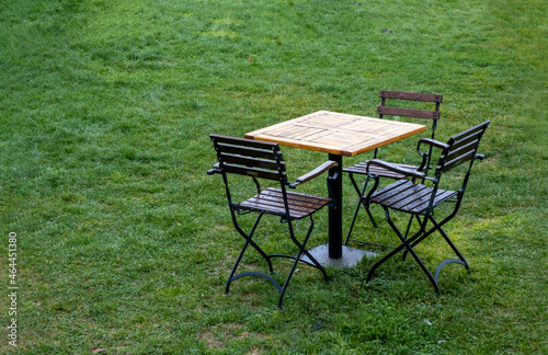 wooden table and iron garden chair on grass floor