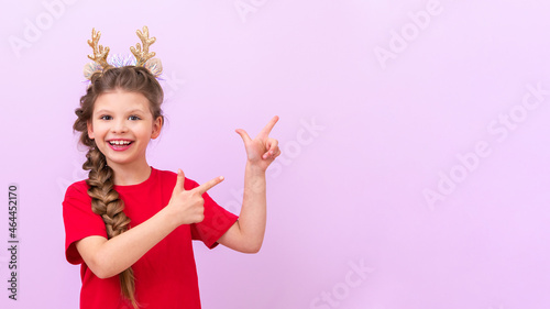A girl with masquerade Christmas horns on her head points to an advertisement about the advent of Christmas.