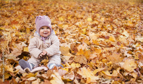 Smiling child playing in park in colorful foliage in autumn