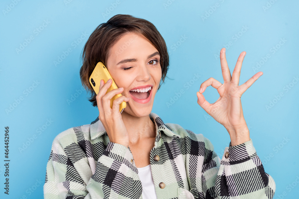 Photo of funny young brunette lady talk telephone wear plaid shirt isolated on blue color background Photo of funny young brunette lady talk telephone wear plaid shirt isolated on blue color background