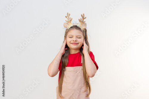 A little teenage girl covered her ears with her hands. Christmas is coming.