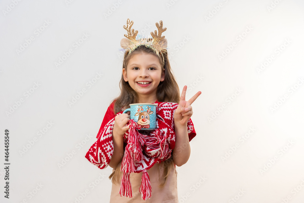 A girl with Christmas horns on her head holds a cup with a drink. A girl with Christmas horns on her head holds a cup with a drink.
