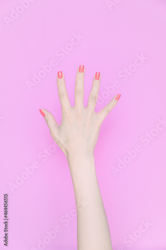 hand showing number five In front of the pink background