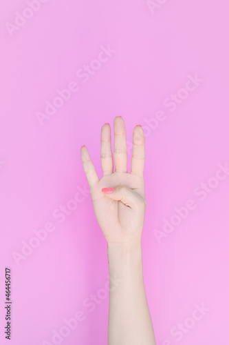 hand showing number four In front of the pink background