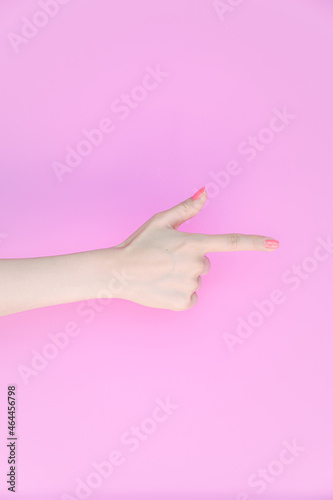 Scissors-shaped hand in front of the pink background