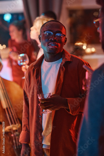 African young man holding glass with alcohol drink he visiting party
