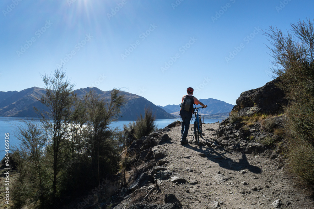 Tourist pushing the bike uphill on Glendhu Bay track along Lake Wanaka, South Island.
