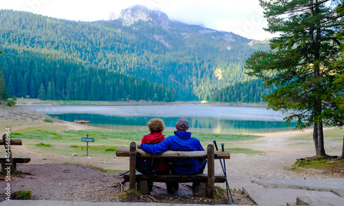 Couple sitting on a bench. Black Lake or Crno Jezero. National park Durmitor 