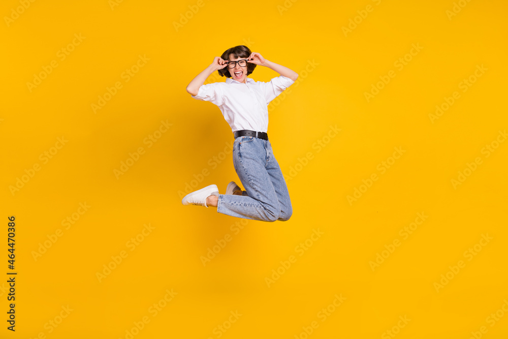 Photo of cheerful business lady jump wear eyeglasses white shirt jeans sneakers isolated yellow color background