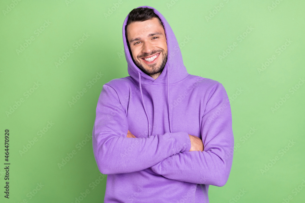 Fototapeta premium Photo of funky young brunet guy crossed hands wear violet hoodie isolated on green color background